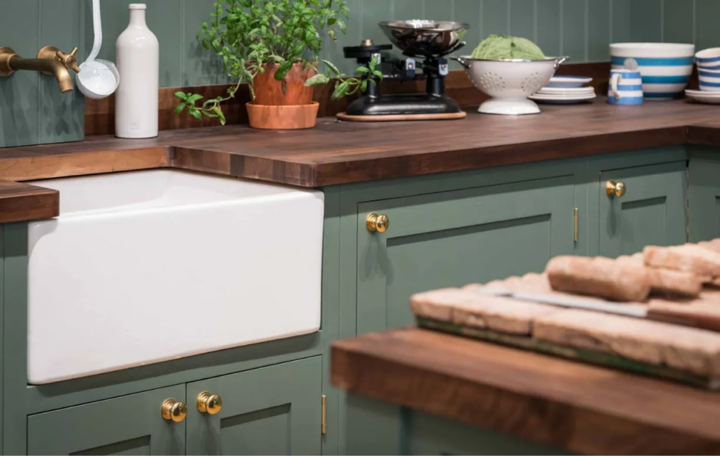 Green shaker kitchen with wood worktop and farmhouse sink