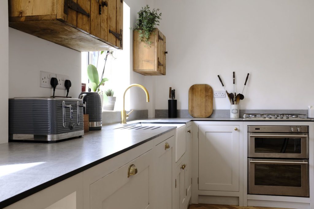 White shaker kitchen with gold details and wooden cupboards