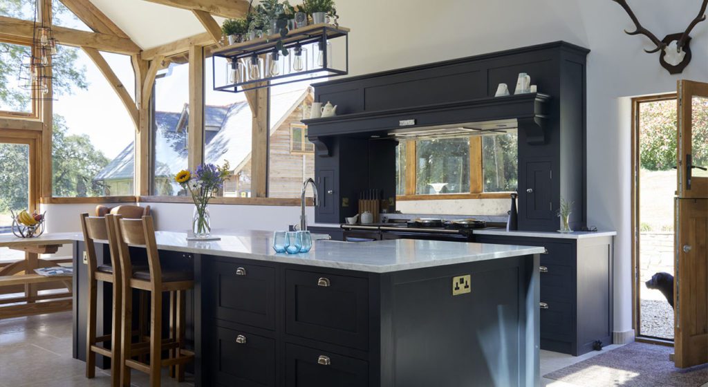 Dark Grey Black shaker Kitchen Design with large island, wooden beams and dog in doorway.