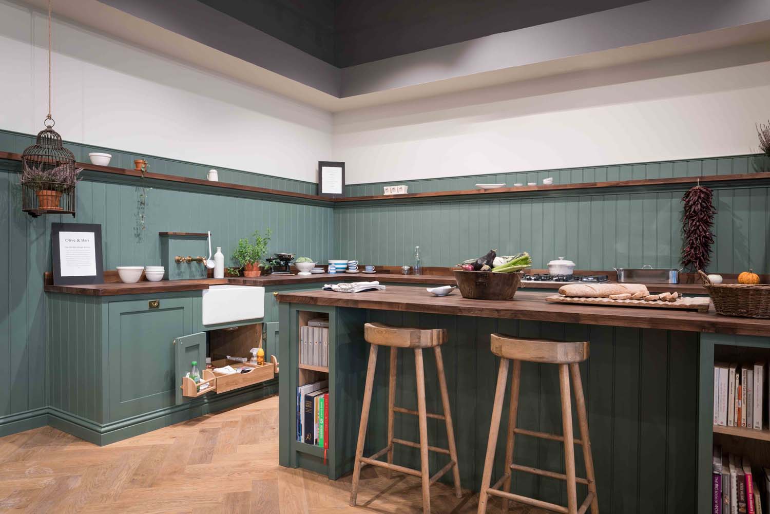 Green shaker kitchen with wooden stools and island